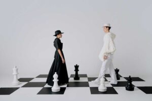 Fashion models in black and white outfits on chessboard floor